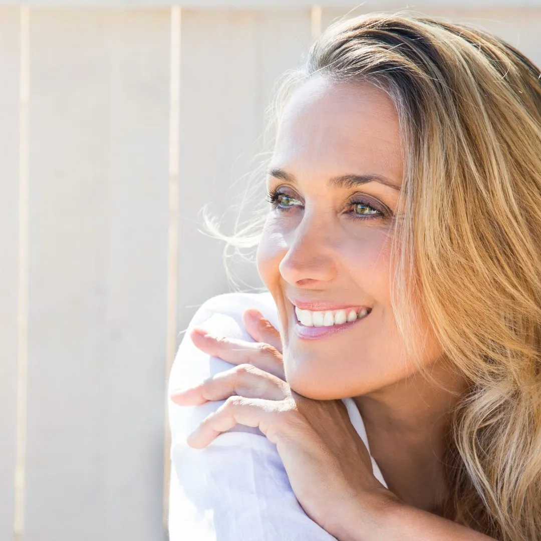 Close-up of a woman smiling naturally in warm light.