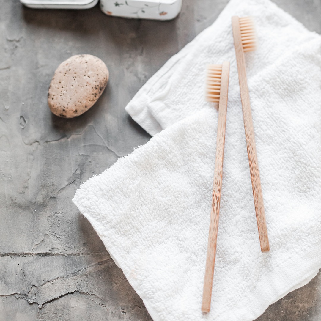 Spa-like flat lay with toothbrushes, towel, and natural dental care details.